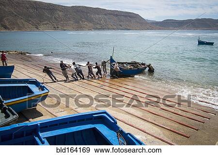Stock Photo - People pulling boat onto boat ramp. Fotosearch