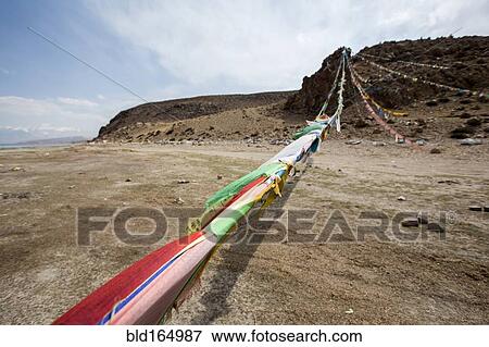 Prayer flags blowing in wind in remote field View Large Photo Image Stock Photo - Prayer flags blowing in wind in remote field. Fotosearch
