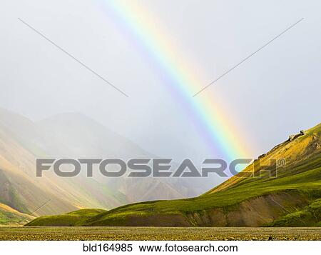 Stock Photography - Rainbow over rural fields and hillside, Landmannalaugar, Fjallabak Nature Reserve, Iceland. Fotosearch