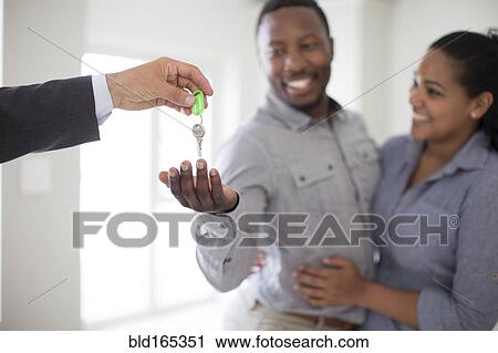 Stock Image - Realtor giving couple keys to new home. Fotosearch