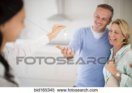 Realtor giving couple keys to new home View Large Photo Image Stock Photography - Realtor giving couple keys to new home. Fotosearch