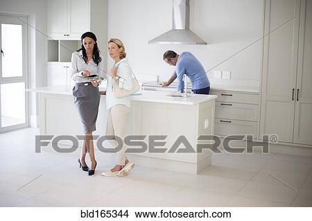 Picture - Realtor showing couple kitchen in new home. Fotosearch