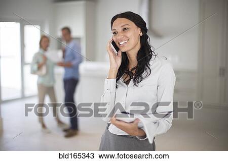 Realtor talking on cell phone with couple in new home View Large Photo Image Stock Image - Realtor talking on cell phone with couple in new home. Fotosearch