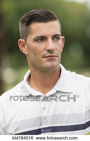 Stock Photograph - Serious Caucasian man standing outdoors. Fotosearch