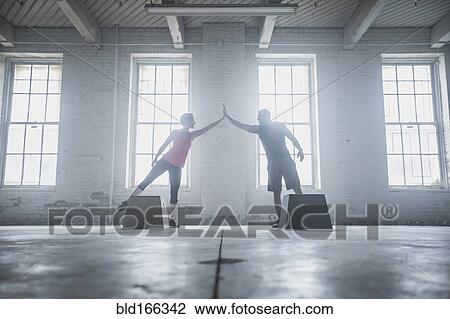 Stock Image - Silhouette of athletes high-fiving near platforms. Fotosearch