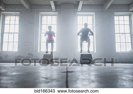 Stock Image - Silhouette of athletes jumping on platforms. Fotosearch