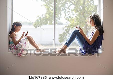 Sisters using technology in window View Large Photo Image Stock Photography - Sisters using technology in window. Fotosearch