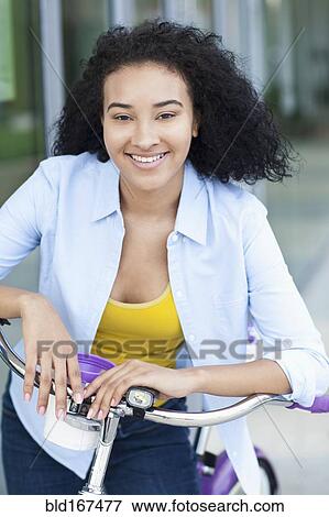 Stock Photo - Smiling Black woman riding bicycle outdoors. Fotosearch
