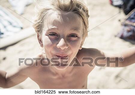 Stock Photography - Smiling Caucasian boy standing on beach. Fotosearch