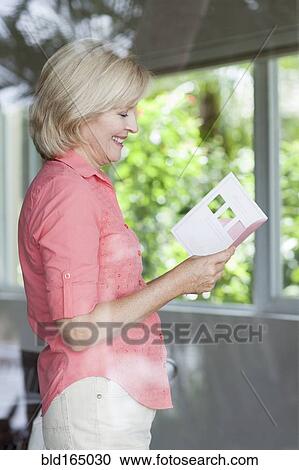 Stock Image - Smiling Caucasian woman reading card. Fotosearch