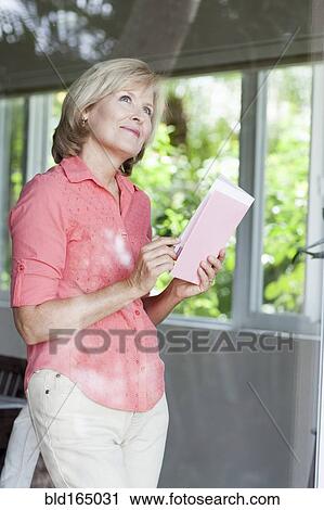 Stock Image - Smiling Caucasian woman reading card. Fotosearch