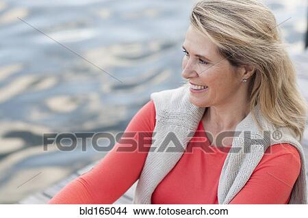 Picture - Smiling Caucasian woman rowing canoe on lake. Fotosearch
