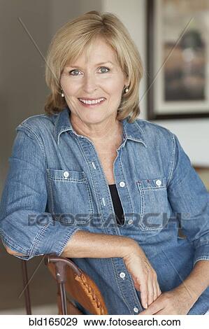 Smiling Caucasian woman sitting in chair View Large Photo Image Stock Photo - Smiling Caucasian woman sitting in chair. Fotosearch