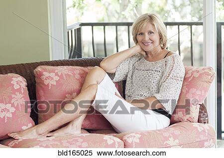 Smiling Caucasian woman sitting on sofa View Large Photo Image Stock Photography - Smiling Caucasian woman sitting on sofa. Fotosearch