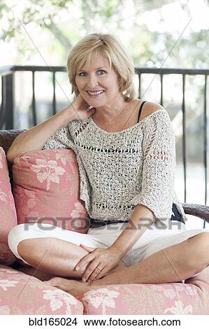 Smiling Caucasian woman sitting cross-legged on sofa View Large Photo Image Picture - Smiling Caucasian woman sitting cross-legged on sofa. Fotosearch