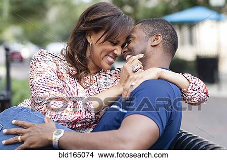 Picture - Smiling couple hugging on park bench. Fotosearch