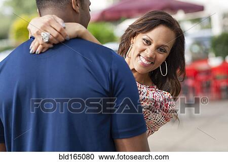 Smiling couple hugging on sidewalk View Large Photo Image Stock Image - Smiling couple hugging on sidewalk. Fotosearch