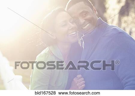 Stock Photo - Smiling couple hugging outdoors. Fotosearch