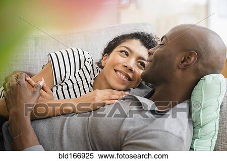 Smiling couple laying on sofa View Large Photo Image Stock Photography - Smiling couple laying on sofa. Fotosearch