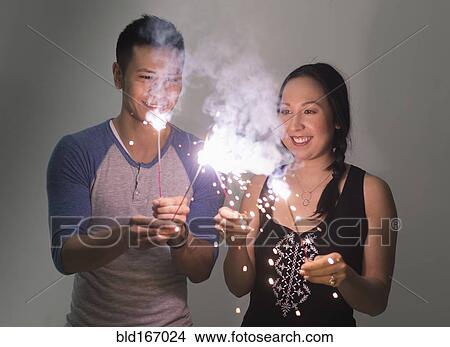 Smiling couple playing with sparklers View Large Photo Image Picture - Smiling couple playing with sparklers. Fotosearch