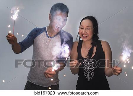 Stock Image - Smiling couple playing with sparklers. Fotosearch