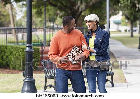 Smiling couple walking in urban park View Large Photo Image Stock Image - Smiling couple walking in urban park. Fotosearch