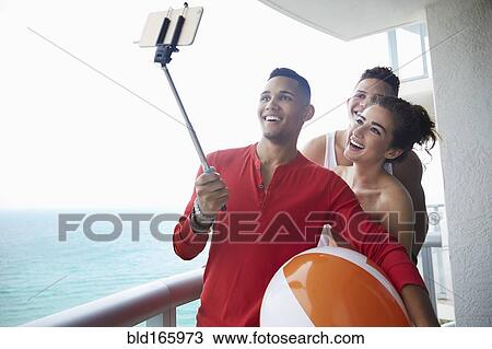 Smiling friends taking selfie on balcony View Large Photo Image Stock Image - Smiling friends taking selfie on balcony. Fotosearch