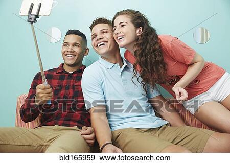Stock Photo - Smiling friends taking selfie together. Fotosearch