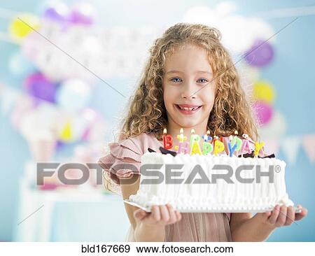 Smiling girl holding birthday cake at party View Large Photo Image Stock Photo - Smiling girl holding birthday cake at party. Fotosearch