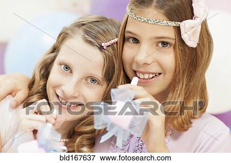 Stock Photo - Smiling girls holding noisemakers at party. Fotosearch