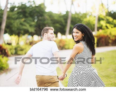 Smiling Hispanic couple walking in park View Large Photo Image Stock Photograph - Smiling Hispanic couple walking in park. Fotosearch