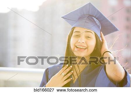 Stock Photo - Smiling Hispanic girl wearing graduation robe and mortarboard. Fotosearch