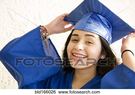 Stock Photograph - Smiling Hispanic girl wearing graduation robe and mortarboard. Fotosearch
