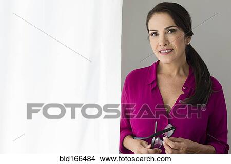 Smiling Hispanic woman holding eyeglasses View Large Photo Image Picture - Smiling Hispanic woman holding eyeglasses. Fotosearch
