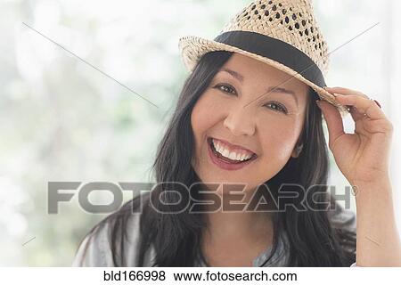 Stock Photo - Smiling mixed race woman wearing straw hat. Fotosearch
