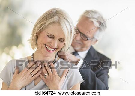 Smiling older Caucasian man giving wife a necklace View Large Photo Image Picture - Smiling older Caucasian man giving wife a necklace. Fotosearch