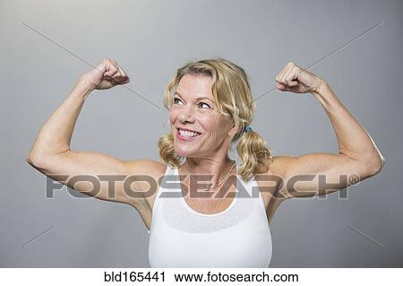 Stock Image - Smiling older woman flexing biceps. Fotosearch