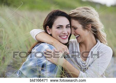 Smiling women hugging on beach View Large Photo Image Stock Image - Smiling women hugging on beach. Fotosearch