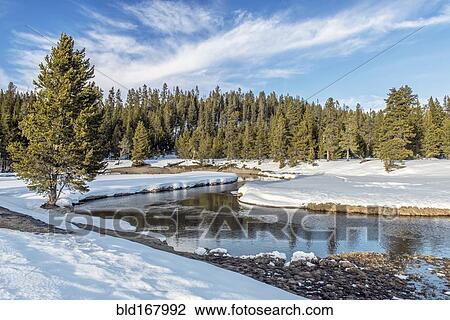 Stock Image - Snowy fields and hills near remote stream. Fotosearch