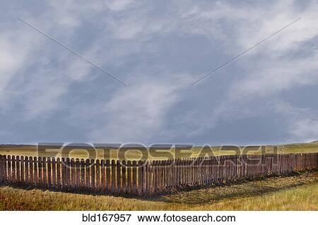 Stock Photo - Storm clouds over rural grass fields and fence. Fotosearch