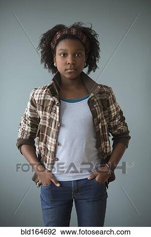Stock Image - Stylish Black girl standing with hands in pockets. Fotosearch