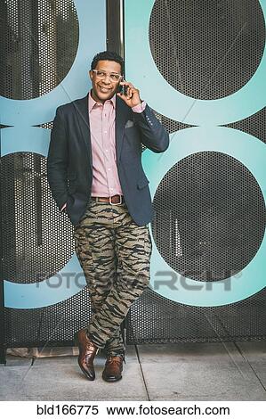 Stock Photography - Stylish Mixed race businessman talking on cell phone outdoors. Fotosearch