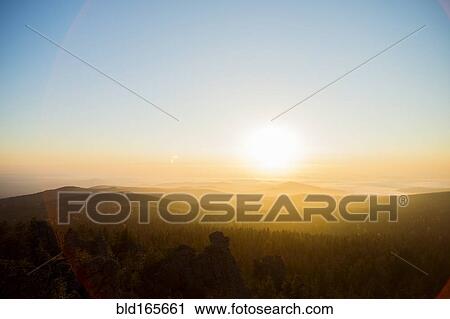 Stock Image - Sunrise over hills in remote landscape. Fotosearch