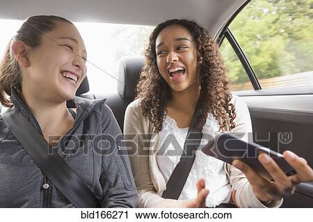 Teenage girls using cell phone in car back seat View Large Photo Image Stock Image - Teenage girls using cell phone in car back seat. Fotosearch