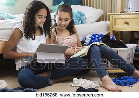 Stock Photo - Teenage girls using digital tablet in bedroom. Fotosearch