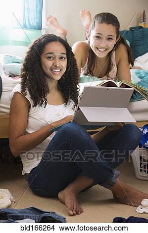 Picture - Teenage girls using digital tablet on bed. Fotosearch