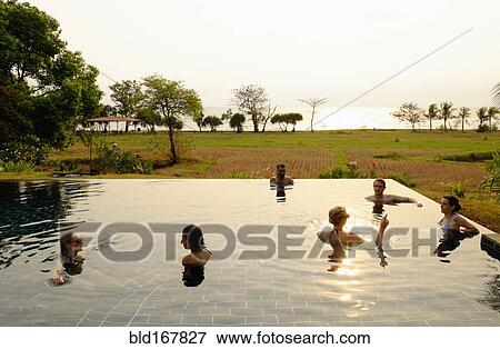 Tourists swimming in infinity pool in remote landscape View Large Photo Image Stock Photo - Tourists swimming in infinity pool in remote landscape. Fotosearch