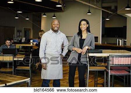Stock Photograph - Waiter and businesswoman smiling in cafe. Fotosearch