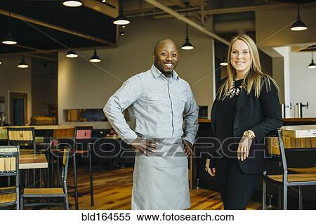 Stock Photography - Waiter and businesswoman smiling in cafe. Fotosearch