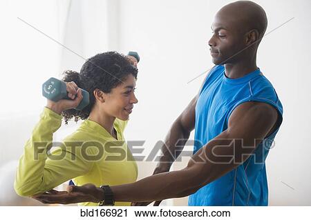 Woman lifting weights with trainer in gym View Large Photo Image Stock Image - Woman lifting weights with trainer in gym. Fotosearch